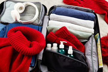 An open suitcase with warm clothes and accessories for winter travel.