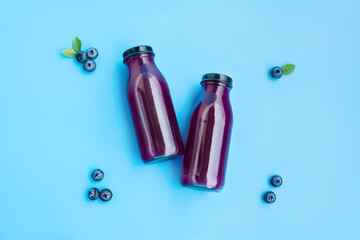 Blueberry juice in glass bottle with ripe blueberry fruits and green leaves isolated on blue background, Fresh Fruit, Healthy Fruit, Healthy Drink