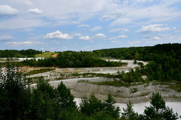 A close up on an old and abandoned chalk or salt mine seen from the top of a tall hill or mountain showing all the places of excavations surrounded with forests and moors seen in summer