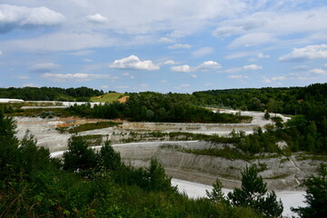 A close up on an old and abandoned chalk or salt mine seen from the top of a tall hill or mountain showing all the places of excavations surrounded with forests and moors seen in summer