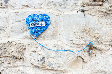 Knitted blue heart with the inscription kidnapped on a stone wall demanding return of all hostages...