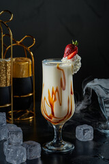Image of a glass of milk and caramel cocktail on a black background with ice cubes