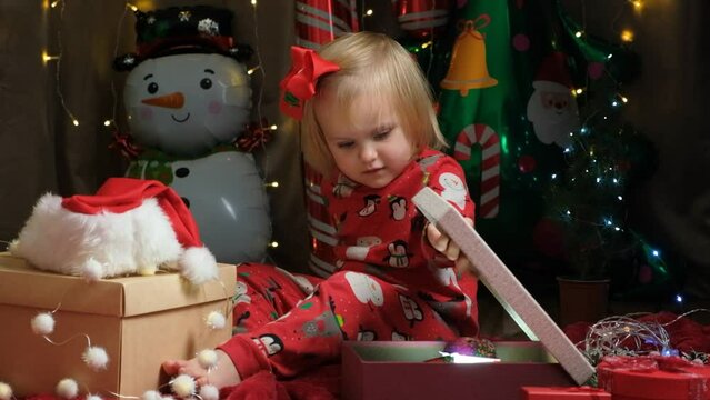 Little cute girl opening Christmas gifts.