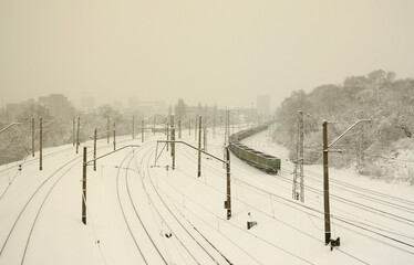 A long train of freight cars is moving along the railroad track. Railway landscape in winter after...