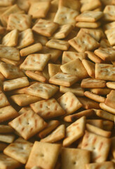 Background texture of small edible squares baked from dough and sprinkled with salt. A lot of salt cracker