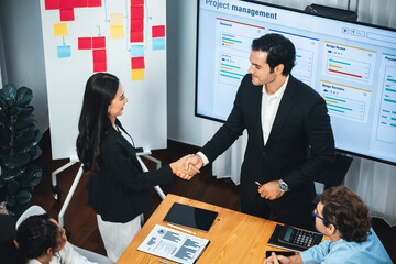 Cheerful meeting room, businesspeople celebrate with handshaking. Successful project was completed...