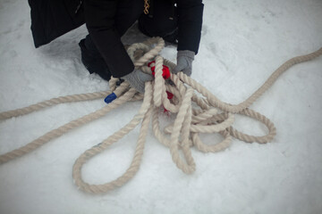 Man lifts rope. Rope in snow. Thick cord.