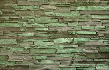 Texture of a stone wall from long and rough stones of different sizes and tones