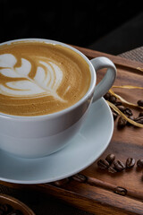 A cup of latte coffee with milk on a dark background and wooden floor