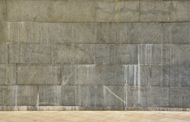 The texture of a wall of large granite tiles that are covered with white streaks when exposed to...