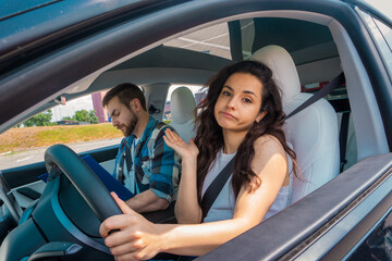 Upset woman sitting in the car during exam while instructor writing notes in the report. Test drive, transportation, safety, education concept