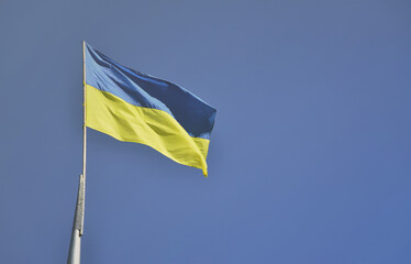 Ukrainian flag against the blue cloudless sky. The official flag of the Ukrainian state includes yellow and blue colors