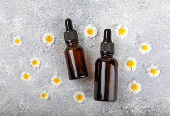Glass bottle with chamomile essential oil on an old wooden background. Chamomile flowers, close up. Aromatherapy, spa and herbal medicine ingredients. Beauty concept.Copy space. Natural cosmetic