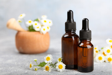 Glass bottle with chamomile essential oil on an old wooden background. Chamomile flowers, close up. Aromatherapy, spa and herbal medicine ingredients. Beauty concept.Copy space. Natural cosmetic
