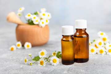 Fototapeta na wymiar Glass bottle with chamomile essential oil on an old wooden background. Chamomile flowers, close up. Aromatherapy, spa and herbal medicine ingredients. Beauty concept.Copy space. Natural cosmetic