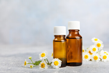 Glass bottle with chamomile essential oil on an old wooden background. Chamomile flowers, close up. Aromatherapy, spa and herbal medicine ingredients. Beauty concept.Copy space. Natural cosmetic