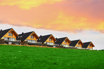 Barnhouse style houses. A street with cozy small houses. Living in the suburban. Concept of mortgage loan. Modern construction. Pros and cons of wooden house and suburban real estate concept.