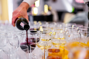 waiter pouring red wine from bottle into a glass in cafe or restaurant