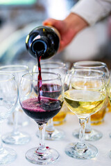 waiter pouring red wine from bottle into a glass in cafe or restaurant