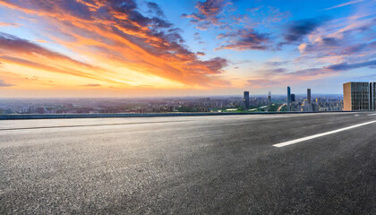 asphalt road and city skyline with colorful sky clouds at sunset
