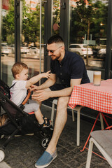 Handsome father spending time with his toddler. Heautiful baby with his father in cafe. Weekend with family and children