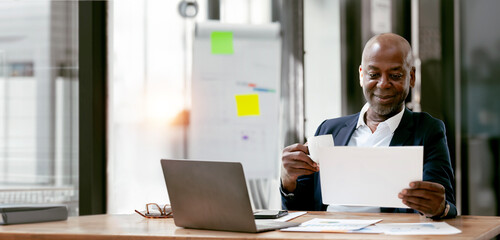 African American Senior businessman smiling and looking at paperwork, successful business concept.