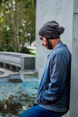 Urban relaxation: Young Caucasian man, profile view, leaning on park wall.