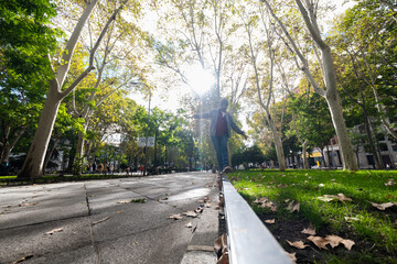 Fototapeta premium Urban equilibrium: Young man, wide-angle perspective, gracefully balances in Madrid's autumn.
