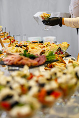 hands of a waiter prepare food for a buffet table in a restaurant