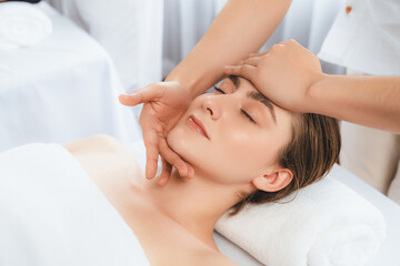 Caucasian woman enjoying relaxing anti-stress head massage and pampering facial beauty skin recreation leisure in dayspa modern light ambient at luxury resort or hotel spa salon. Quiescent - obrazy, fototapety, plakaty