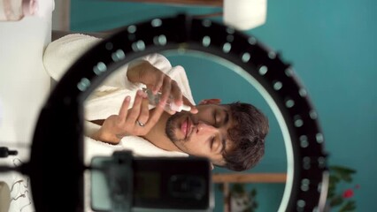 Arabic beauty male blogger filming daily skin care routine tutorial at camera. Social media influencer livestreaming cosmetics product review in home studio. Male cosmetic product