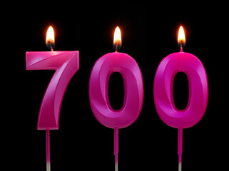 Burning pink birthday candles isolated on black background, number 700.