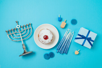 Jewish holiday Hanukkah top view composition with menorah, traditional donuts and gift box on blue background. Flat lay - obrazy, fototapety, plakaty