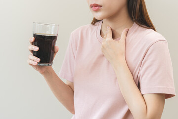 Acid reflux disease, suffer asian young woman, girl hand holding a glass of cola, have symptom gastroesophageal, heartburn pain on chest when drinking sparkling, soft water. Healthcare medical concept - obrazy, fototapety, plakaty