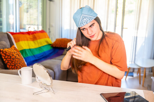 Transgender person combing using a mirror in the living room