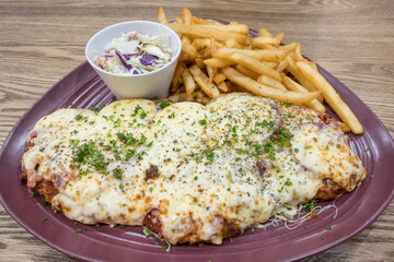 Giant breaded chicken schnitzel with four cheeses and salami with chips in Adelaide, Australia