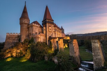 Fototapeta na wymiar an old castle with a bridge at dusk and the sky is blue: Corvin Castle Hunedoara Romania