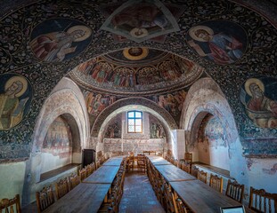 An exquisite ancient church featuring a plethora of detailed paintings on its arched ceiling