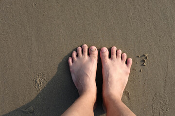 Asian Woman's feet on the sandy beach with natural sunlight. Summer sea top view