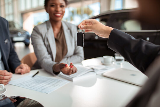 Close up man giving car keys to woman at the dealership