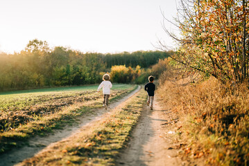 Little happy boys twins running countryside road. Rural childhood, autumn,family