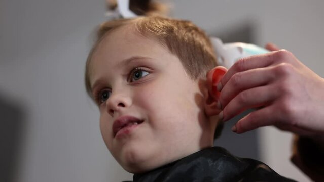mom cuts her son hair with hair clipper at home, Poland