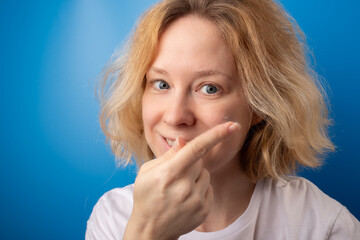 woman putting on contact eye lenses on blue background