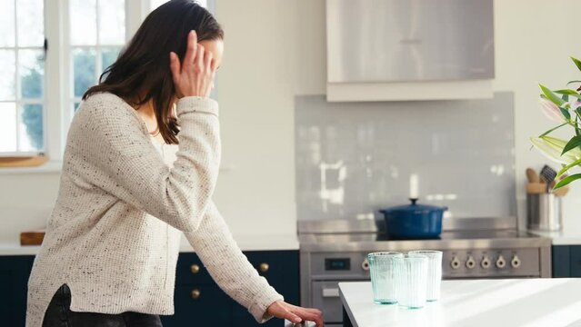 Woman At Home In Kitchen Doing Chores Loading Glasses Into Integrated Dishwasher - Shot In Slow Motion