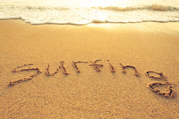 The word surfing written in the sand on the beach