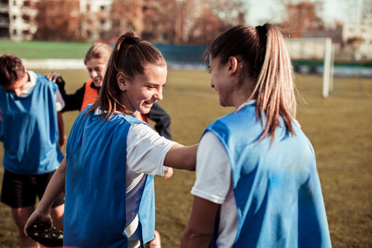 Female football players stretching balancing on each other during practice