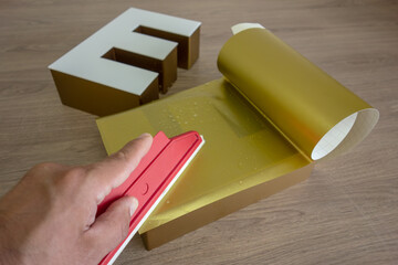 pasting a gold film on a plastic outdoor advertising logo. Production of three-dimensional letters...