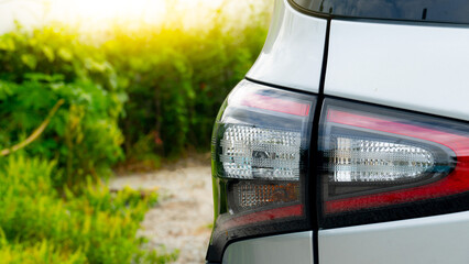 Rear side view of the silver taillights of a parked silver sedan. It is parked in an open area...