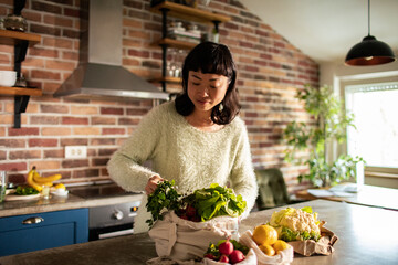 Asian Woman Preparing Fresh Vegetables in a Sunlit Kitchen