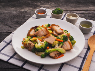 Stir fried mixed vegetables with crispy pork in plate on wooden table background. Thai Food